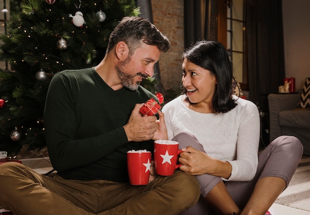 Foto gratuita mujer sorprendida mirando a su cónyuge con un regalo