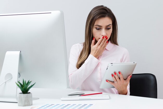 Mujer sorprendida mirando su tableta y cubriendo su boca