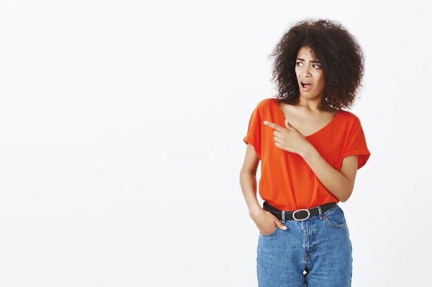 Mujer sorprendida con peinado afro posando en el estudio