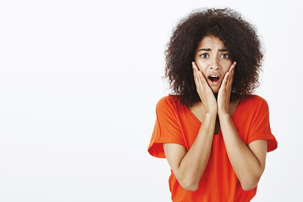 Mujer sorprendida con peinado afro posando en el estudio