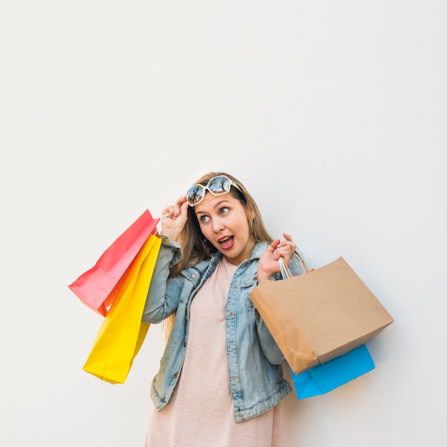 Foto gratuita mujer sorprendida de pie con bolsas de compras en la pared de luz