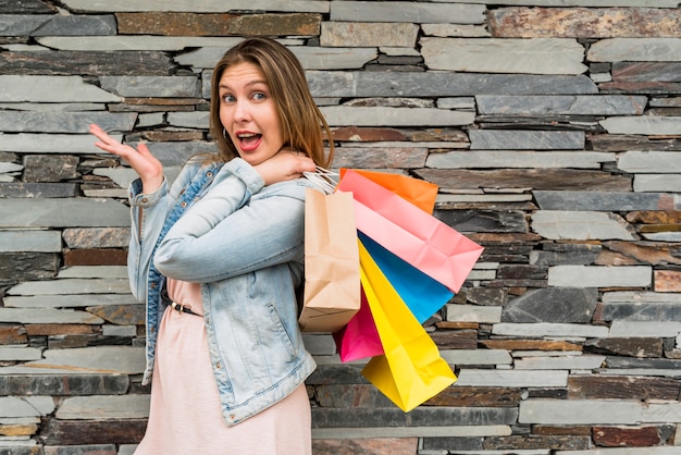 Mujer sorprendida de pie con coloridos bolsos de compras