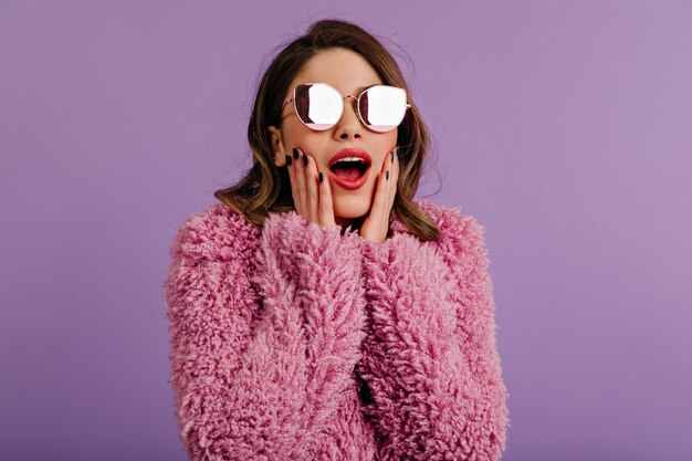 Mujer sorprendida posando en elegantes gafas brillantes