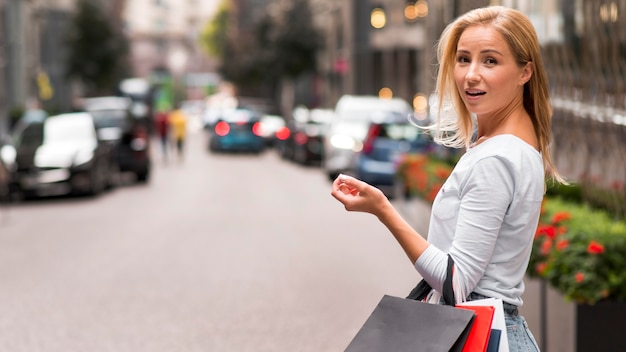 Mujer sorprendida posando sosteniendo bolsas de compras al aire libre