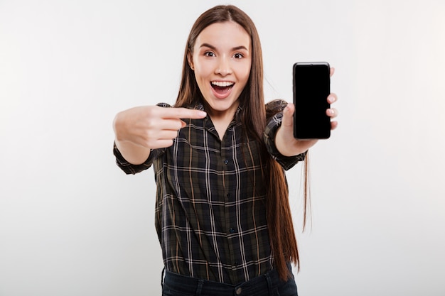 Mujer sorprendida que muestra la pantalla del teléfono inteligente en blanco