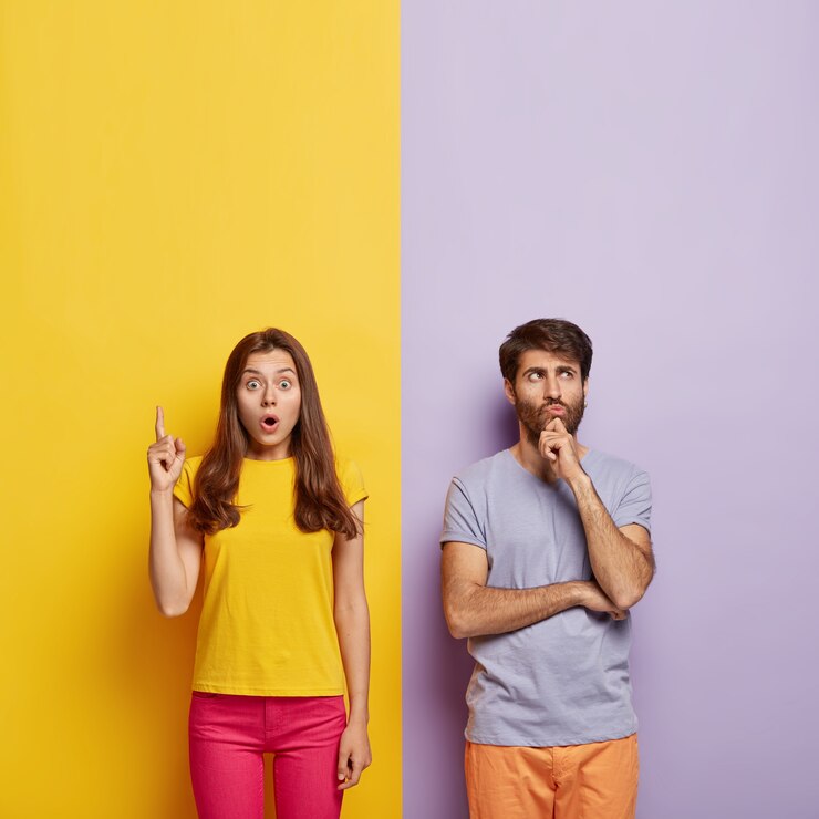 Foto gratuito mujer sorprendida señala hacia arriba, mantiene la boca abierta, hombre sin afeitar pensativo sostiene la barbilla