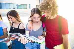 Foto gratuita mujer sorprendida señalando el libro de texto para el hombre