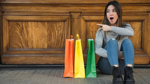 Mujer sorprendida sentada cerca de paquetes de compras