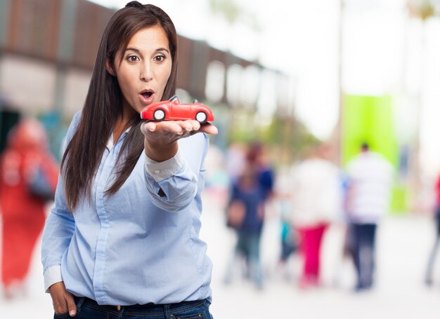 Mujer sorprendida sosteniendo un coche rojo