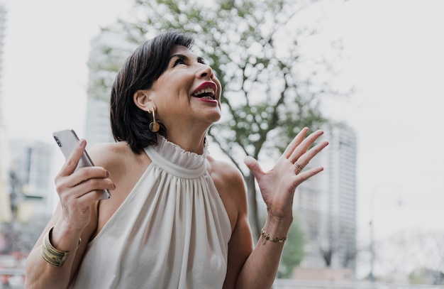 Foto gratuita mujer sorprendida sosteniendo un teléfono al aire libre