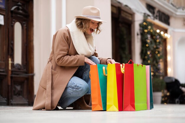 Mujer sorprendida de tiro completo con bolsas de colores