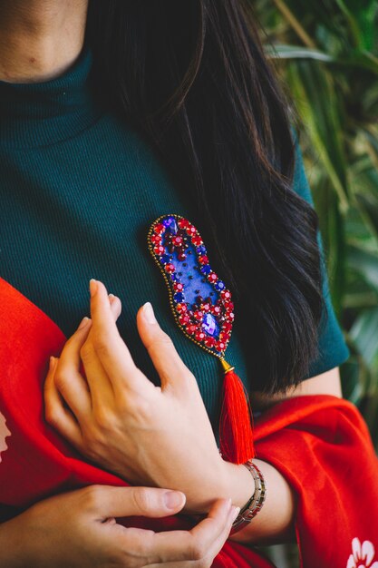 Mujer sosteniendo un alfiler rojo con piedras