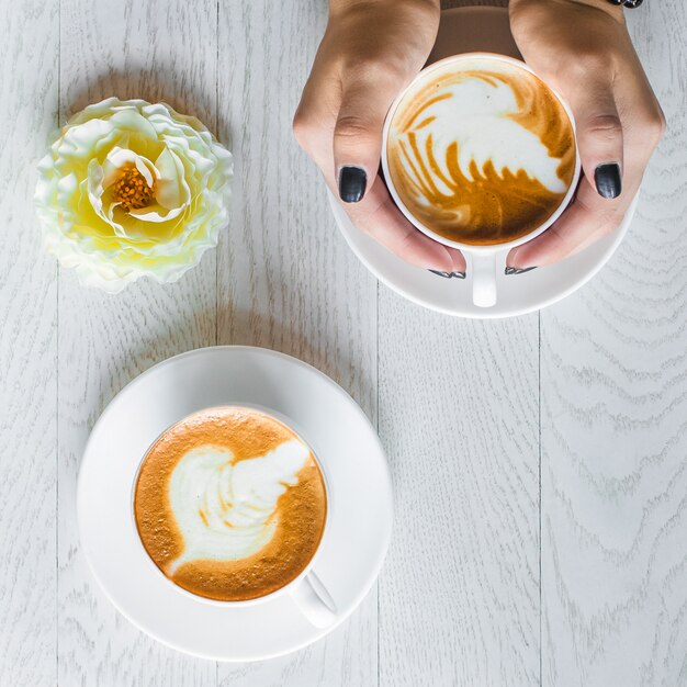 Mujer sosteniendo con ambas manos una de las tazas de café con leche