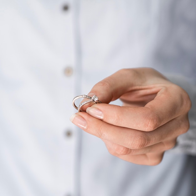 Mujer sosteniendo anillos de compromiso y matrimonio