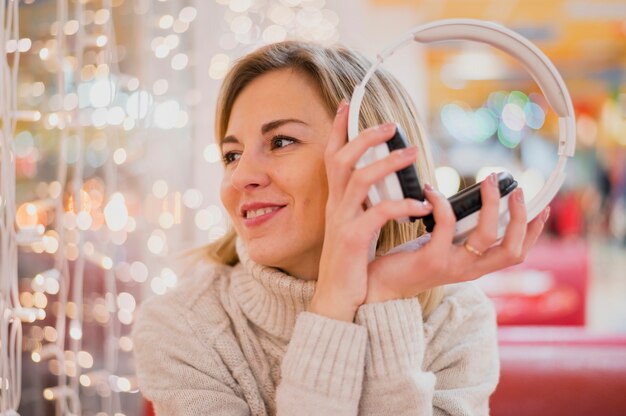 Mujer sosteniendo auriculares mirando las luces de navidad
