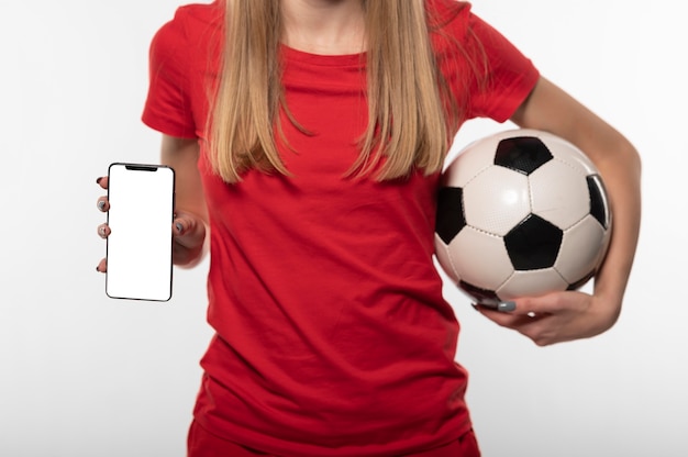 Mujer sosteniendo un balón de fútbol y teléfono de cerca