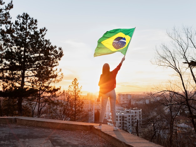 Mujer sosteniendo la bandera brasileña tiro completo