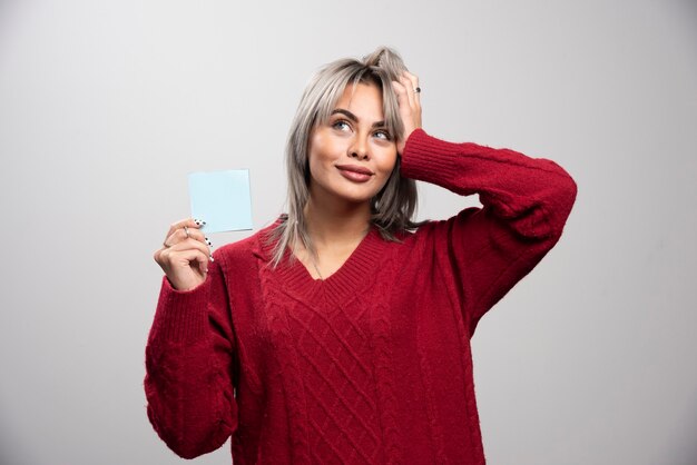 Mujer sosteniendo bloc de notas y pensando en algo.