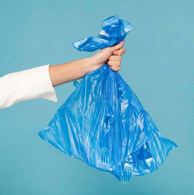 Mujer sosteniendo una bolsa de basura de plástico azul