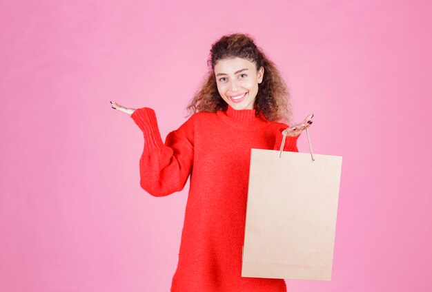 mujer sosteniendo una bolsa de cartón y parece satisfecha.