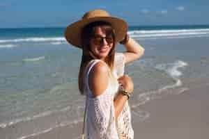 Foto gratuita mujer sosteniendo una bolsa de paja y caminando por la playa
