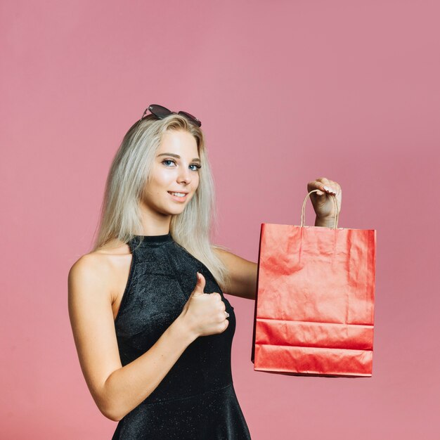 Mujer sosteniendo la bolsa de papel y mostrando el pulgar hacia arriba