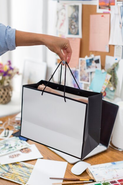 Mujer sosteniendo una bolsa de regalo sobre el escritorio