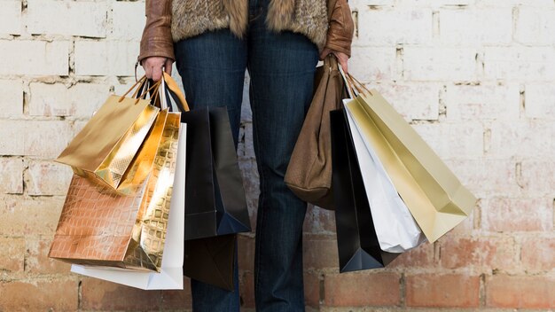 Mujer sosteniendo bolsas de compras cerca de la pared