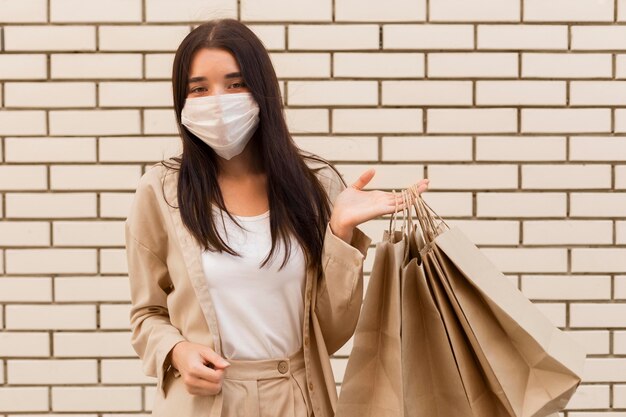 Mujer sosteniendo bolsas de compras y vistiendo máscara