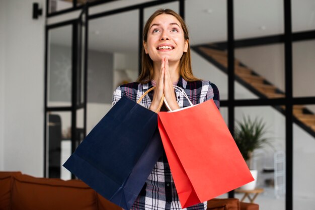 Mujer sosteniendo bolsas de papel y rezando