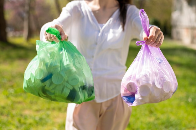 Mujer sosteniendo bolsas de plástico con basura