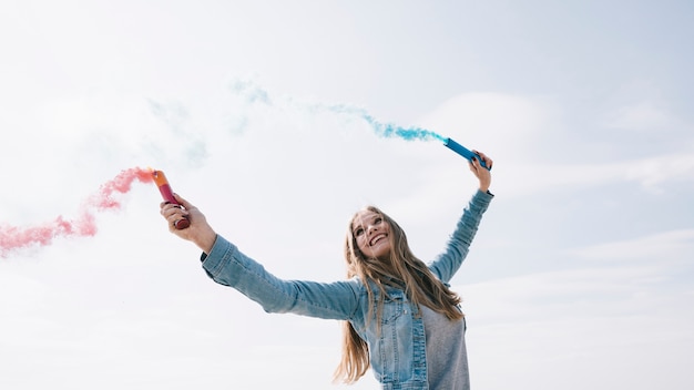 Foto gratuita mujer sosteniendo bombas de humo de colores