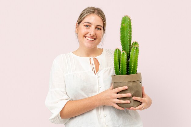 Mujer sosteniendo cactus en macetas en envases sostenibles