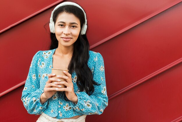 Mujer sosteniendo un café y con auriculares