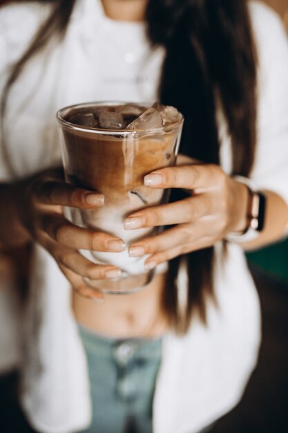 Mujer sosteniendo café con leche frío con hielo