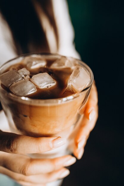 Mujer sosteniendo café con leche frío con hielo