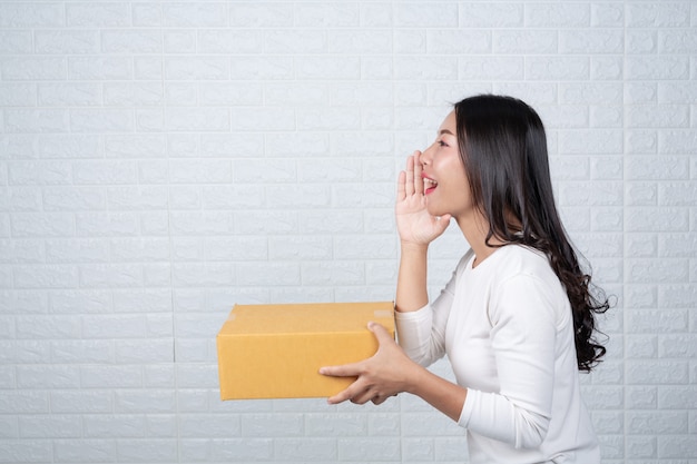 Mujer sosteniendo una caja de correos marrón Hizo gestos con lenguaje de señas.