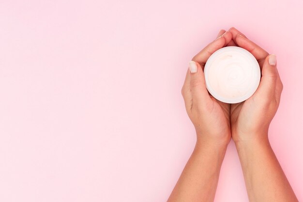 Mujer sosteniendo una caja de crema facial con espacio de copia