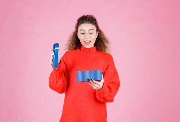 mujer sosteniendo una caja de regalo con forma de corazón azul y abriéndola.