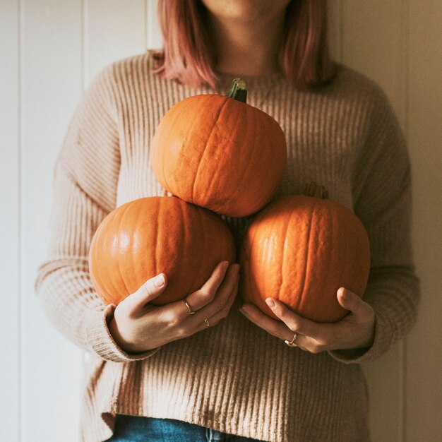 Mujer sosteniendo calabazas de Halloween en una granja