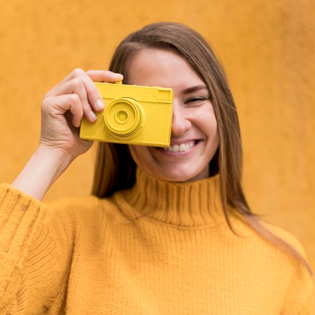 Foto gratuita mujer sosteniendo una cámara amarilla