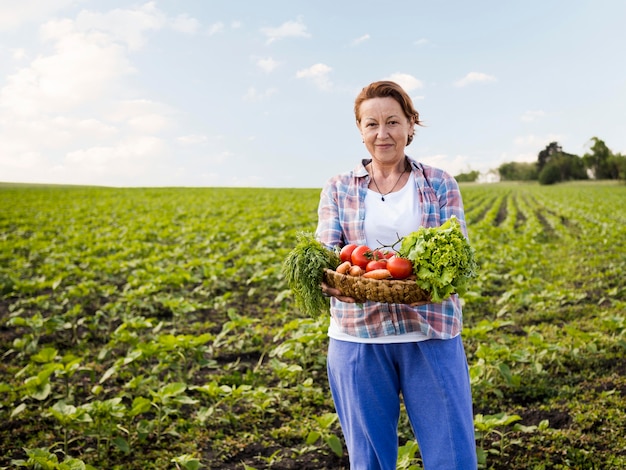 Mujer sosteniendo una canasta llena de verduras con espacio de copia