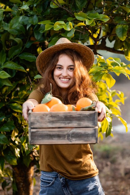 Mujer sosteniendo una canasta con naranjas