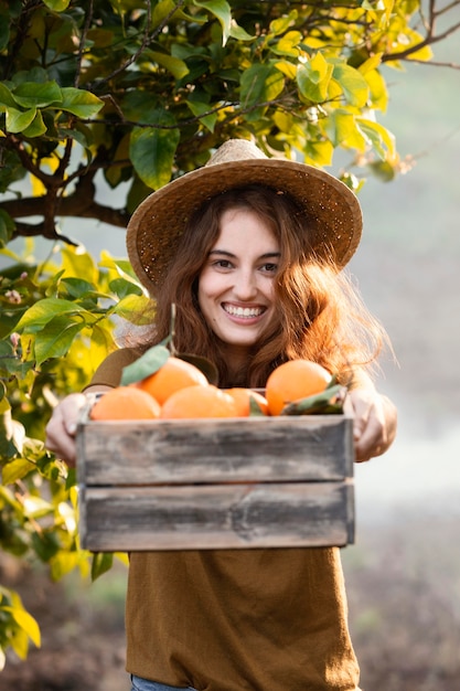 Mujer sosteniendo una canasta con naranjas