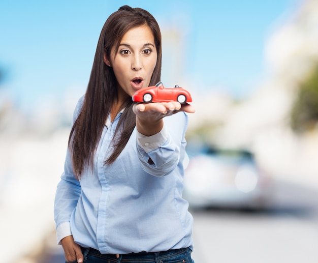 Foto gratuita mujer sosteniendo un coche de juguete de color rojo con fondo borroso
