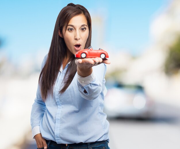 Mujer sosteniendo un coche de juguete de color rojo con fondo borroso