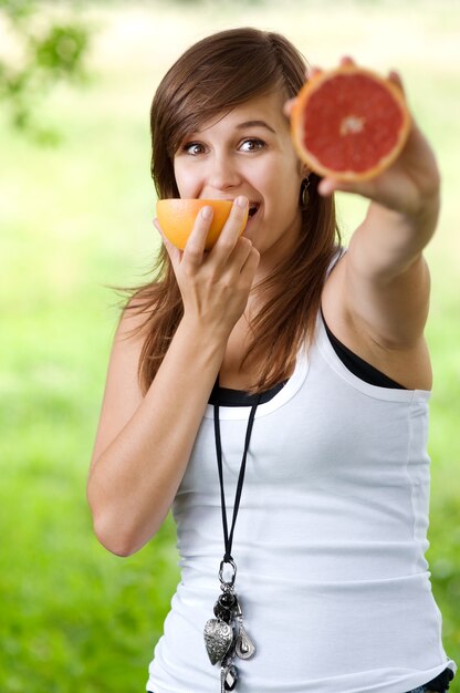 Mujer sosteniendo y comiendo pomelo