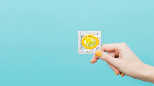 Mujer sosteniendo un condón amarillo