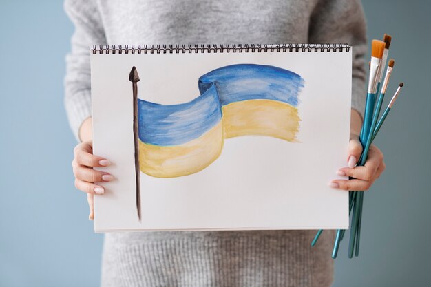 Mujer sosteniendo cuaderno con dibujo de bandera ucraniana