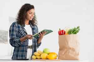 Foto gratuita mujer sosteniendo un cuaderno junto a la bolsa de verduras